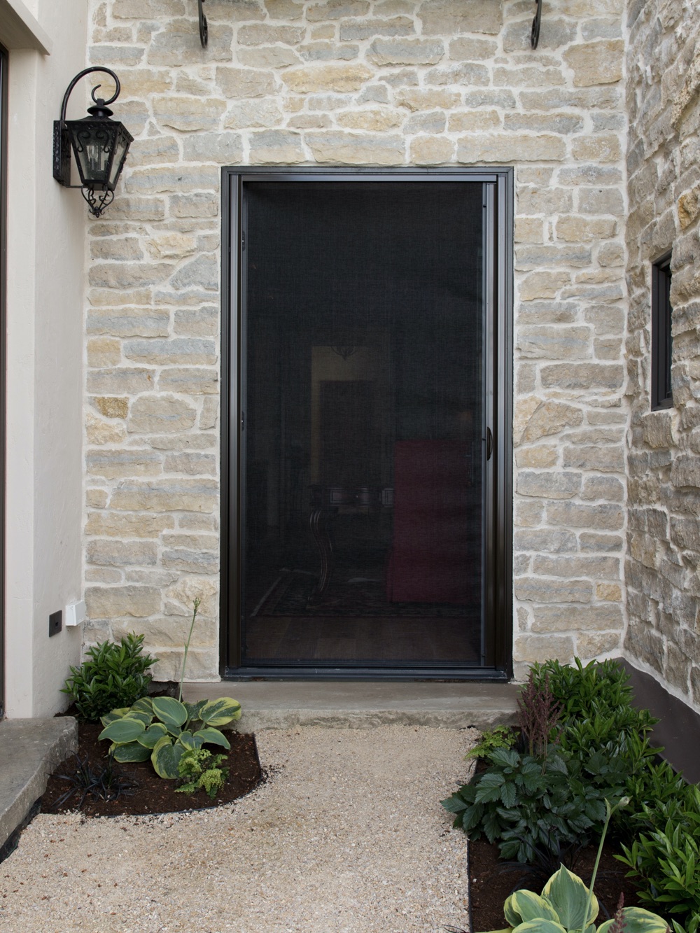 single retractable screen door in front of stone